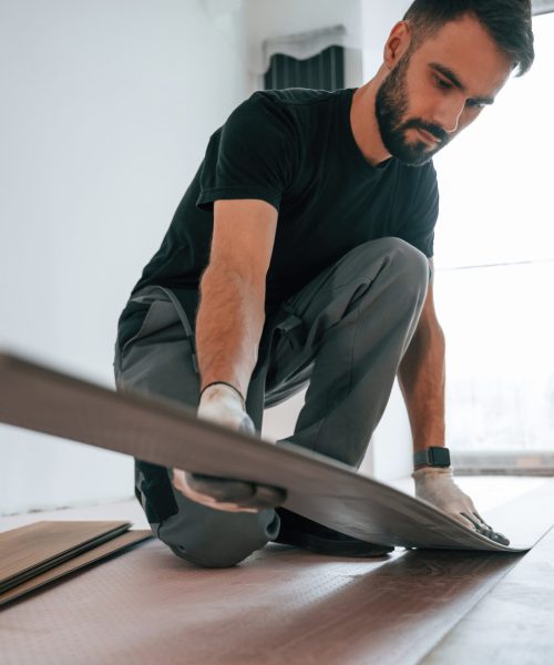 Fitting the planks. Man is installing new laminated wooden floor.